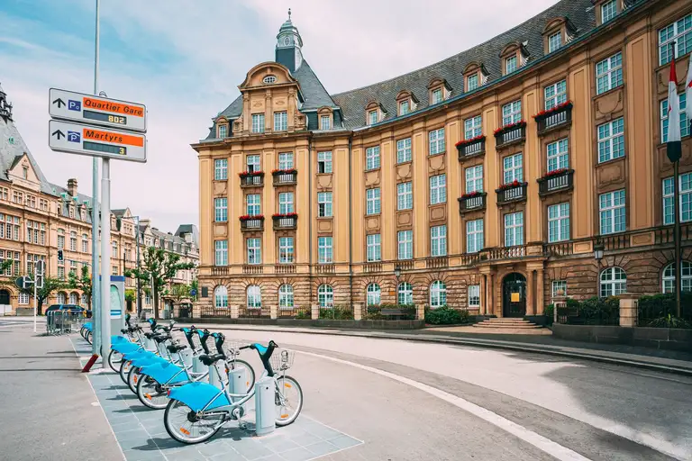 Row of city bikes for rent in front of an ornate bank building facade