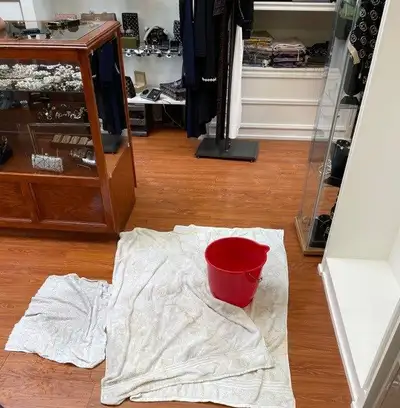 A bucket catching water from a roof leak indoors